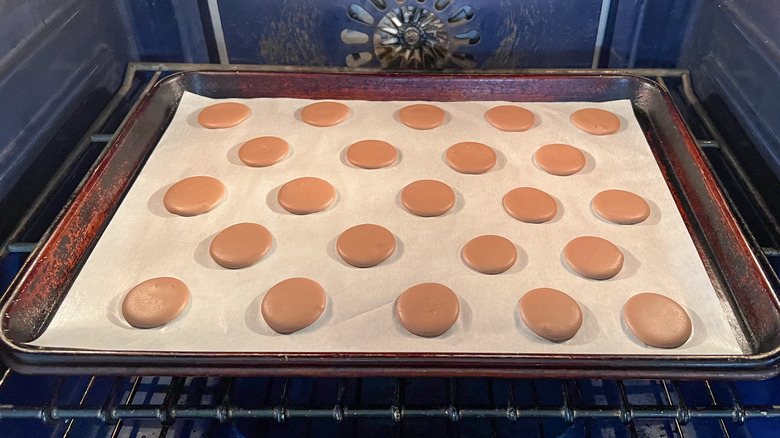 Chocolate macaron shells baking in oven