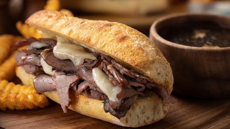 French dip on a plate with jus and fries