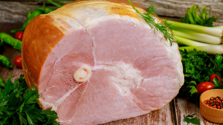 a bone in ham surrounded by vegetables