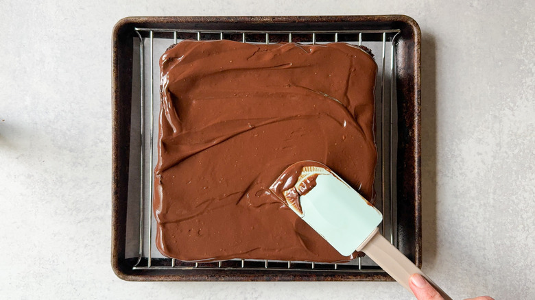 Spreading ganache over brownies on rack