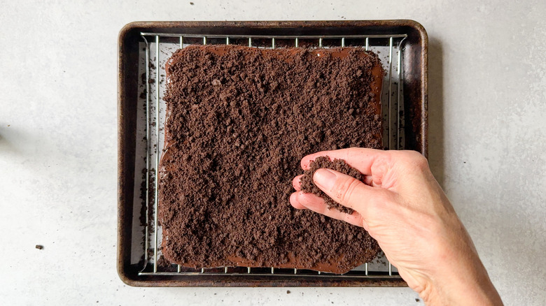 Sprinkling cookie crumbs over ganache