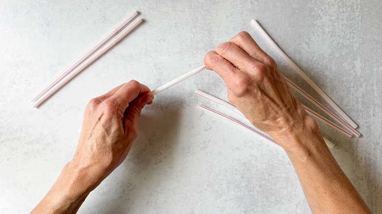 Pulling on flexible straws to straighten them