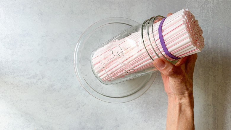 Bundled straws in glass jar set in glass bowl