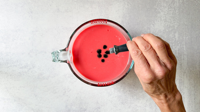 drops of green food coloring in red mixture