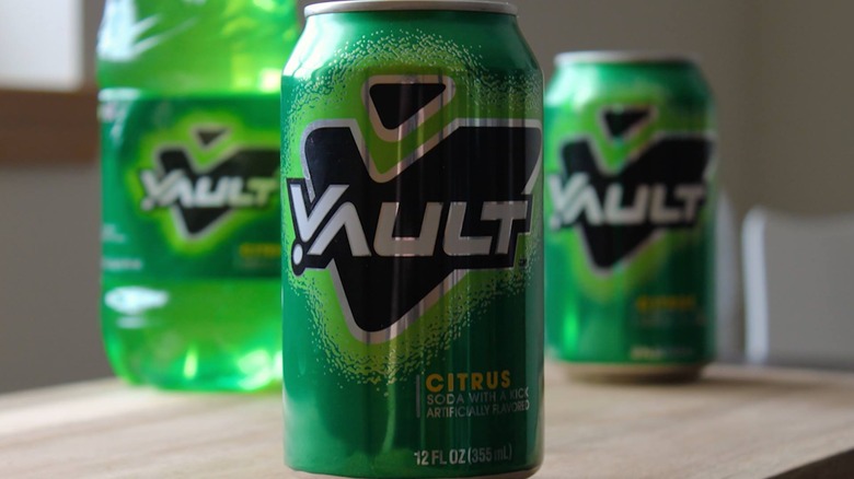 A green can of Vault soda in front of other Vault drinks