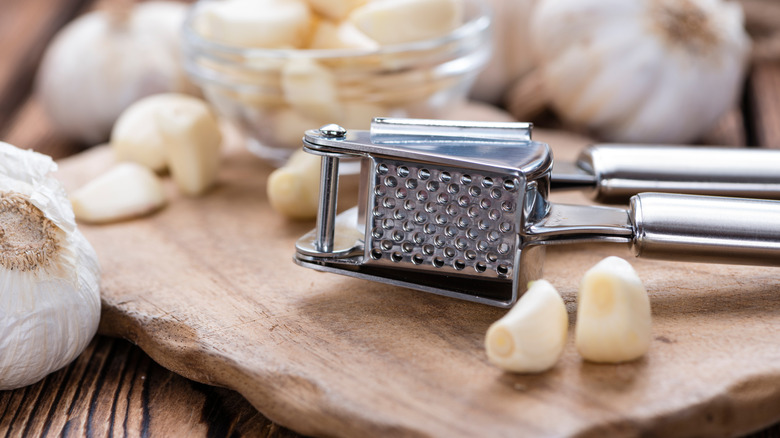 Garlic press surrounded by garlic