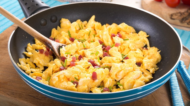 Skillet with scrambled eggs, chopped pickled onions, and chives