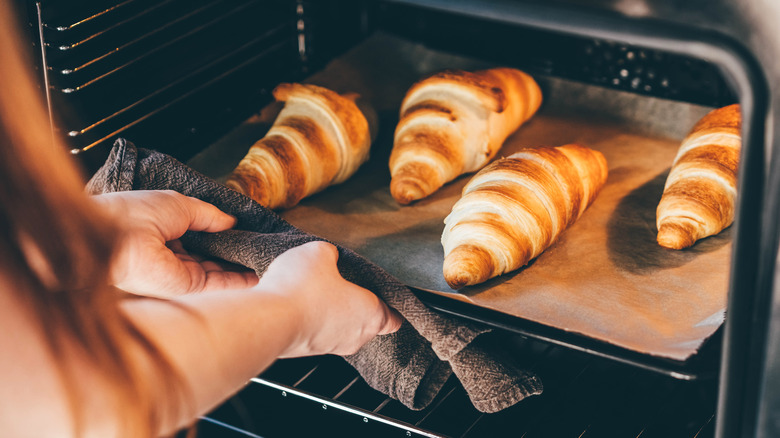 tray of croissants going into oven