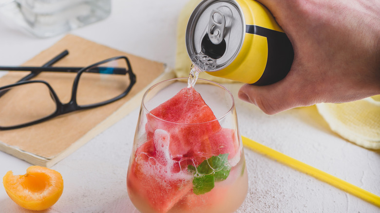 Pouring a canned drink over frozen watermelon cubes