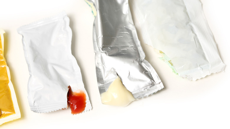 Opened packets of sauce on white background