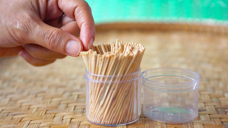 hand reaching into toothpick container