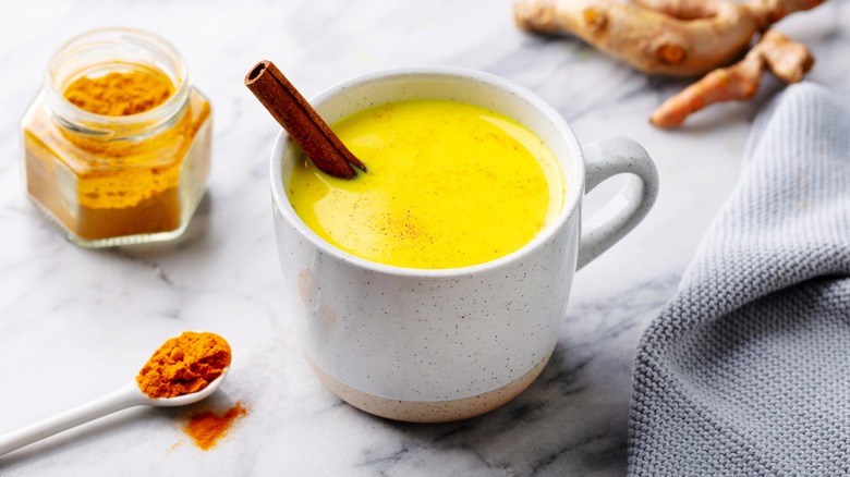 golden turmeric latte in a mug with a cinnamon stick