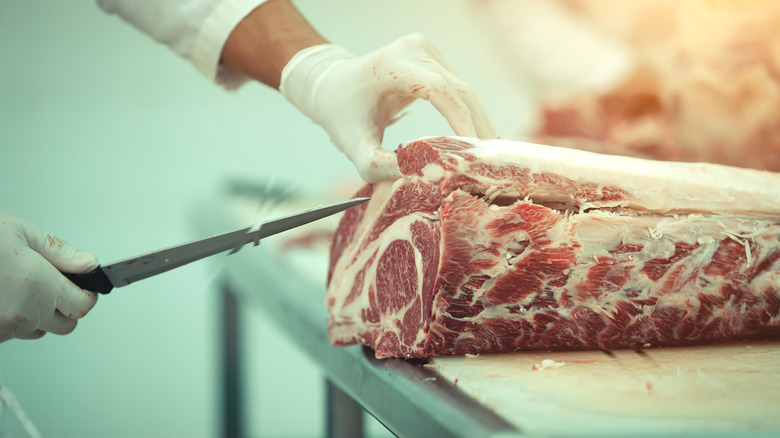 Butcher cutting beef with a knife