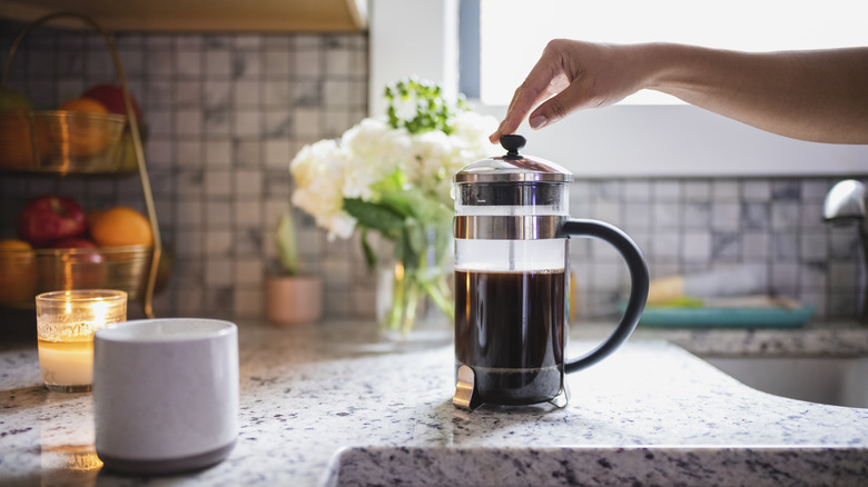 Hand touching a French press