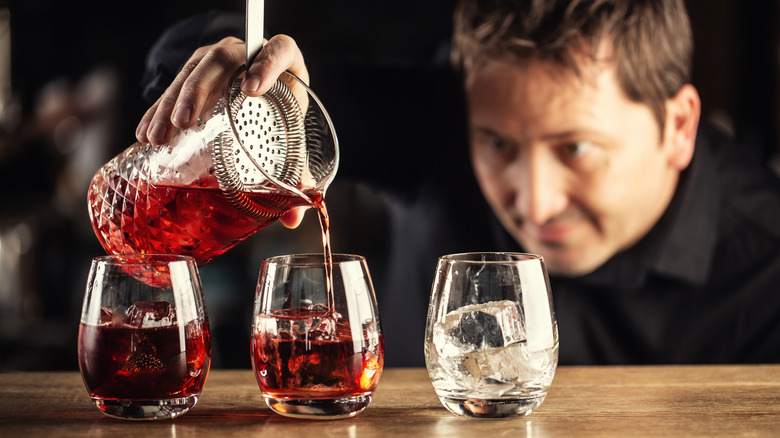 Bartender pours Negroni into cups