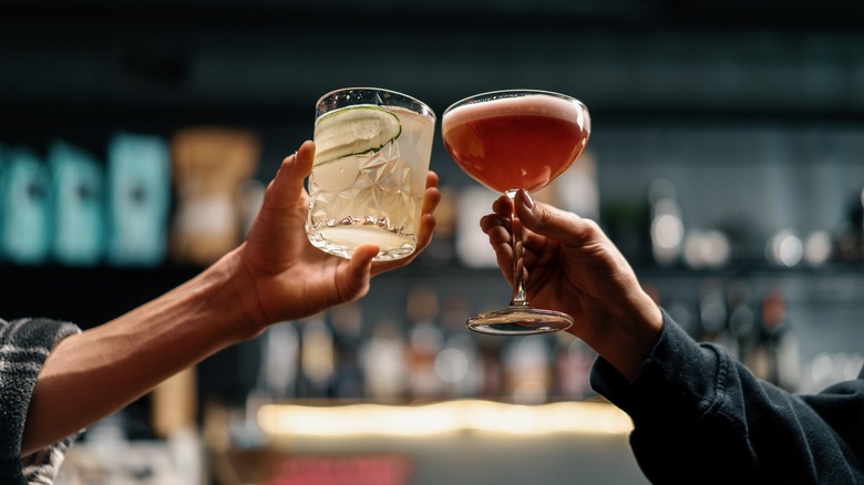 Two hands toasting with cocktails