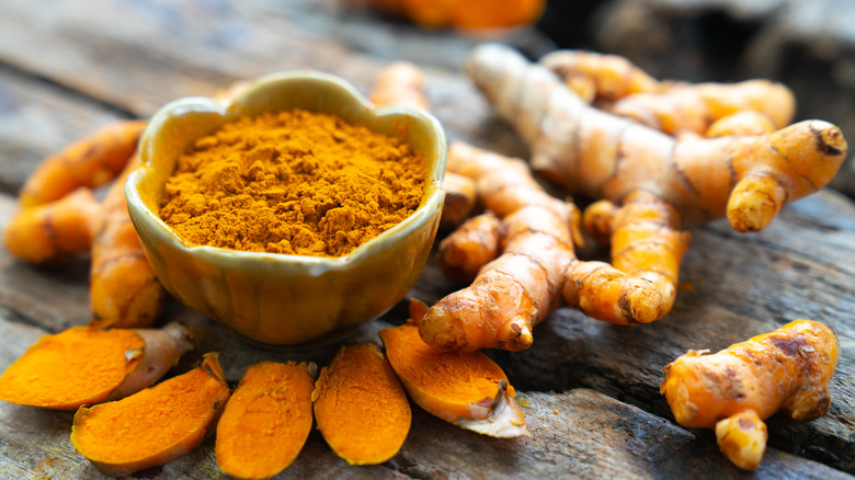 Fresh turmeric root and a bowl of turmeric powder