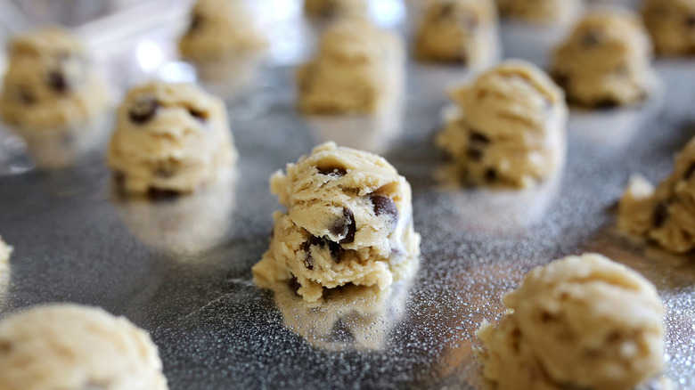 Balls of raw cookie dough on sheet pan