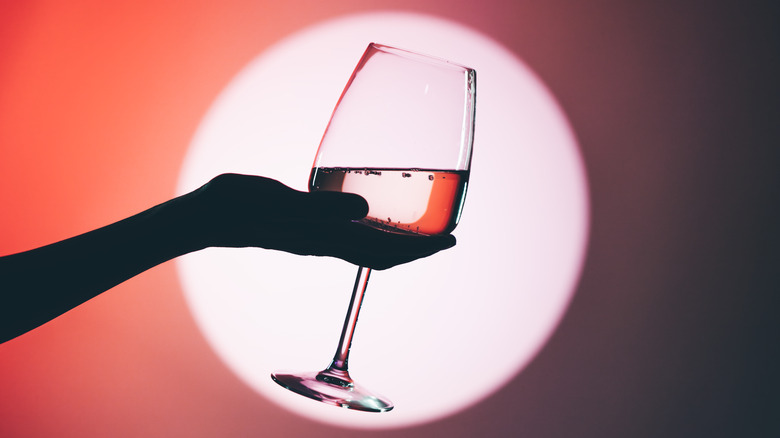 Silhouette of hand holding of wine in front of a light