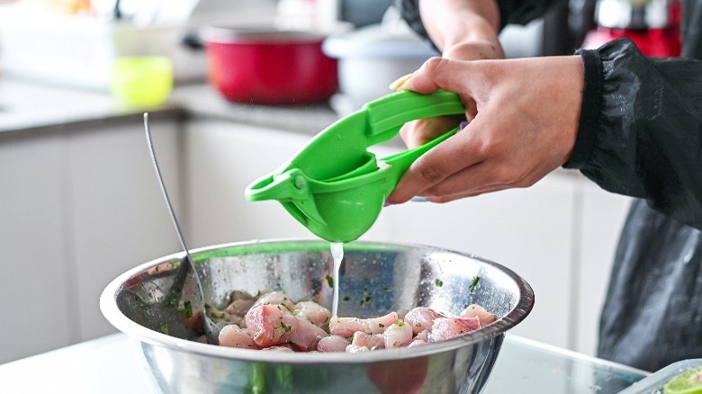 Using a manual juicer to squeeze lime into ceviche