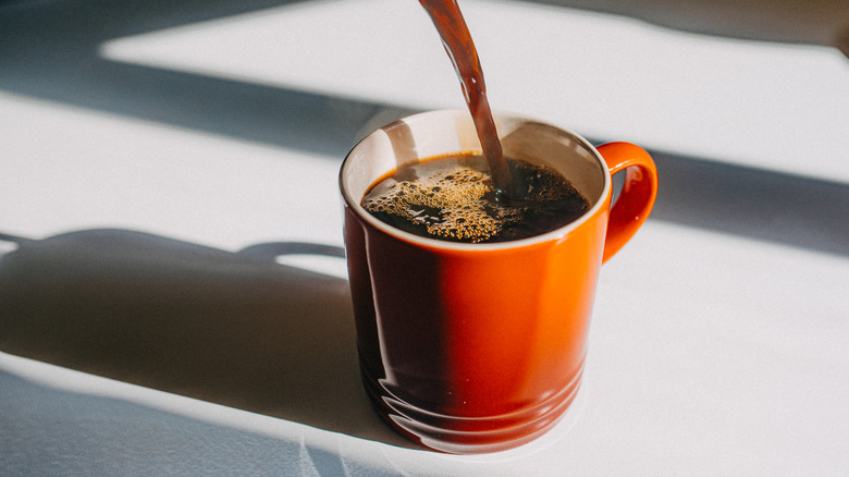 Coffee pouring into an orange mug