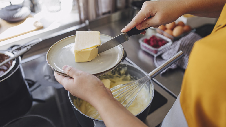 A woman slicing butter on a plate