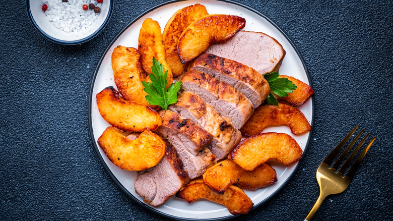 Sliced pork tenderloin on a plate with grilled peaches