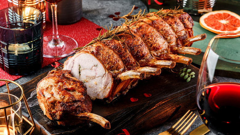 A pork roast on a table with a glass of red wine in the foreground