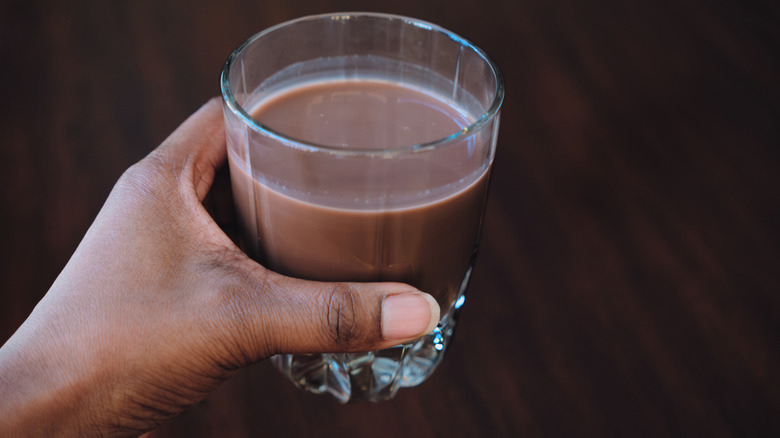 Hand holding a glass of almond chocolate milk