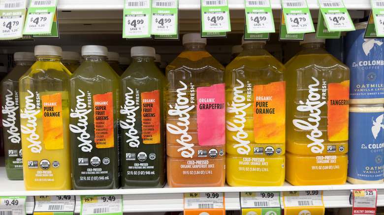 Evolution Fresh juice bottles are lined on a store shelf.