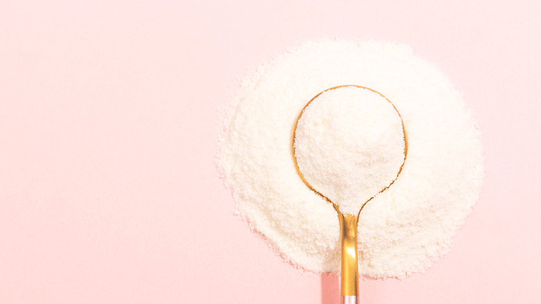 White powder on spoon on pink background.