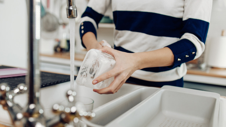 Person washing a container over the sink