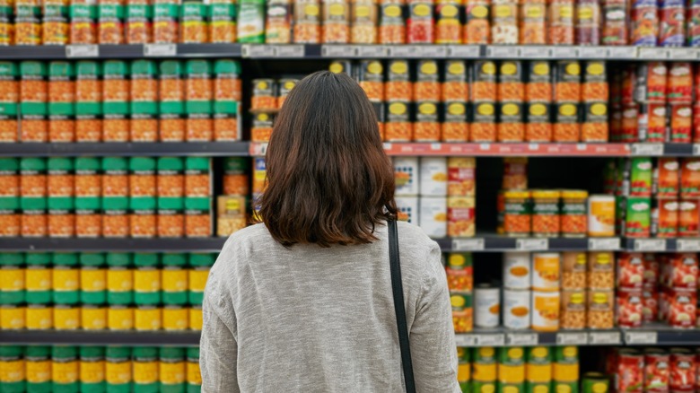 woman looking at shelves of canned goods