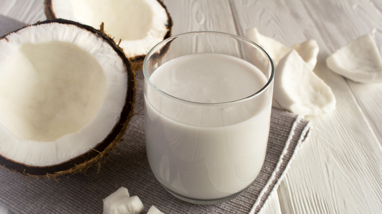 coconut milk in glass with halved coconuts