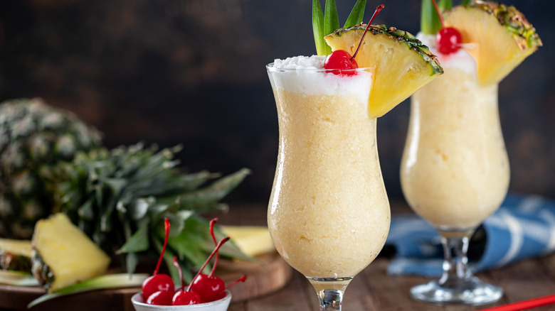 two piña colada cocktails with pineapple garnish and cherries