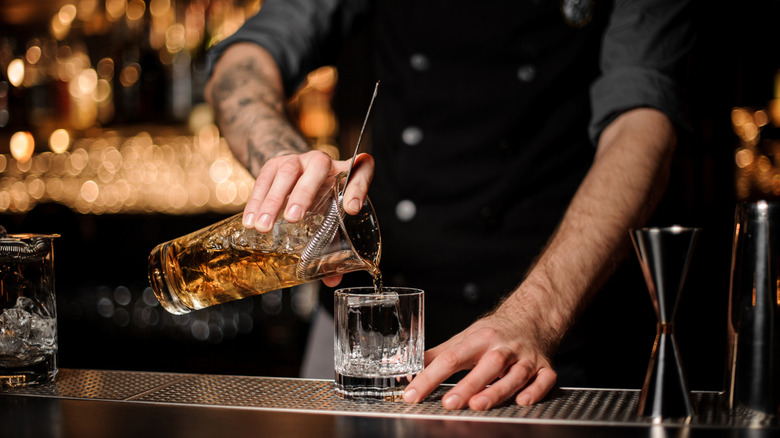 bartender pouring cocktail through strainer