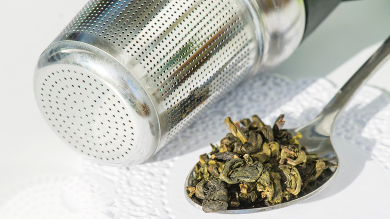 green tea in spoon next to strainer