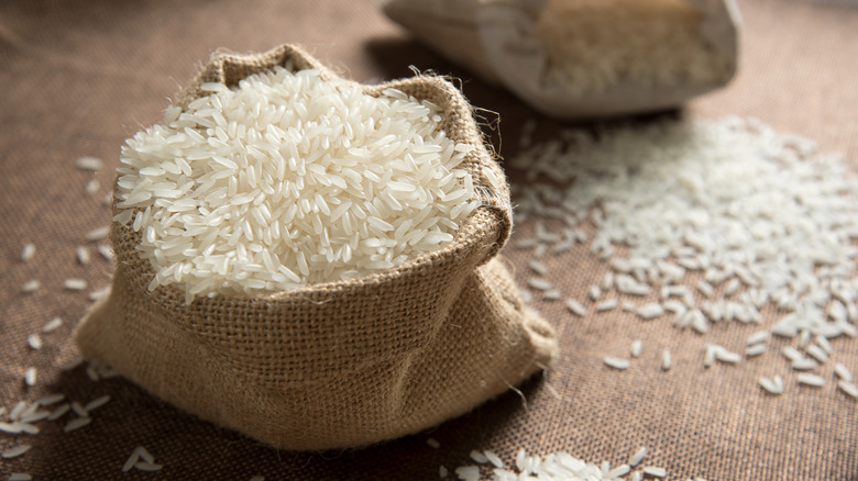 A bag of rice with loose grains around it