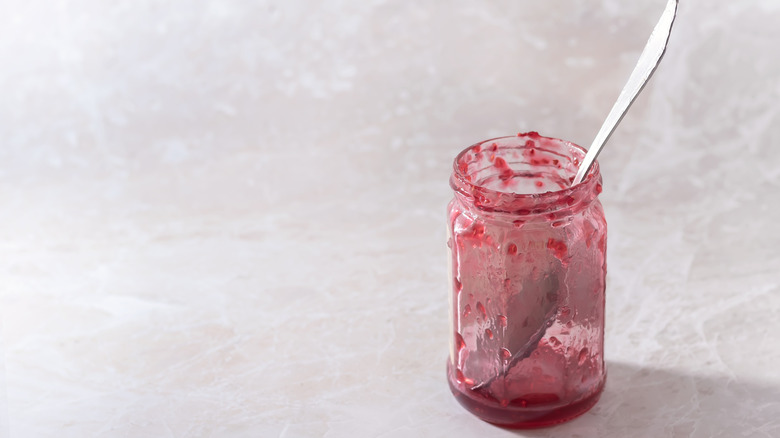 An almost empty jar of jam with a spoon