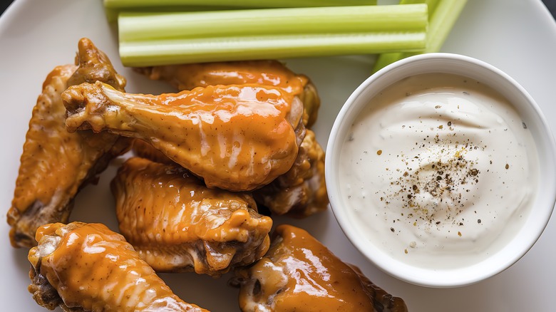 A plate of glazed chicken wings with celery sticks.