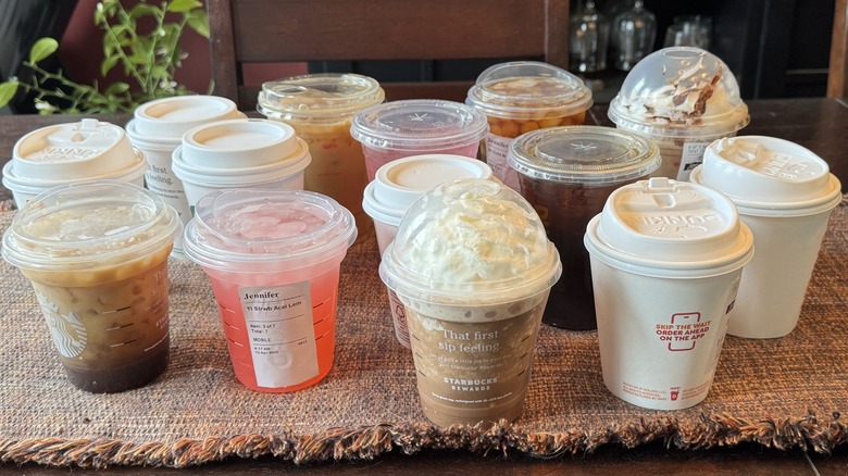 An assortment of specialty drinks from Starbucks and Dunkin' spread out on a table