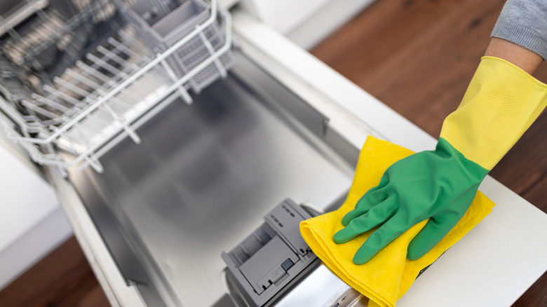 gloved hand cleaning a dishwasher