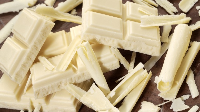 white chocolate chunks and curls on a wooden cutting board