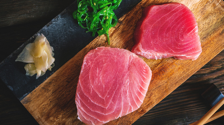 Fresh, raw tuna steaks on a cutting board.