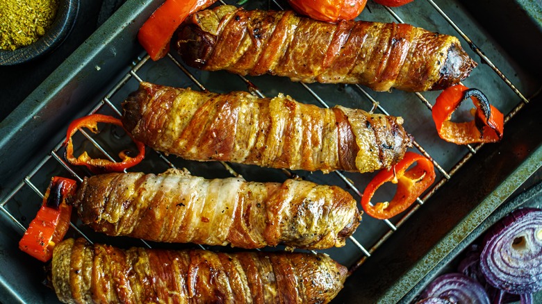 Bacon wrapped sausages on grill