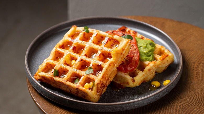 waffles on a black plate with corn, syrup, chorizo, and guacamole