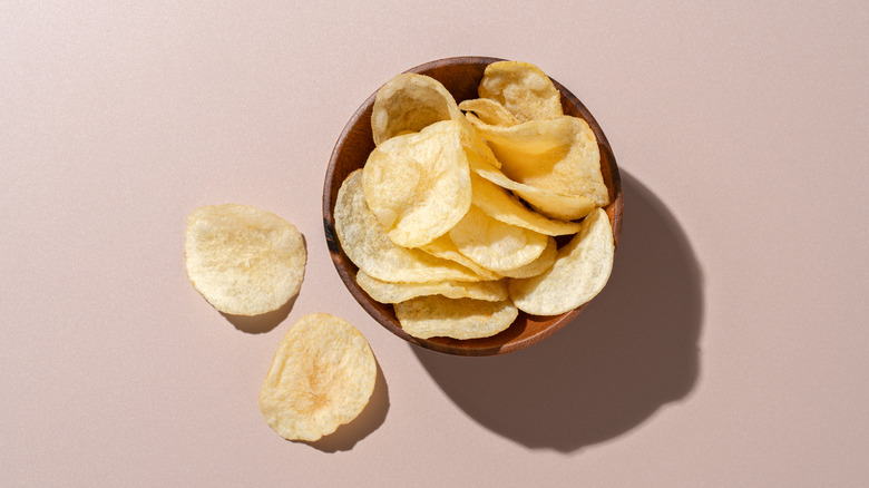 Bowl of potato chips against a pale pink background