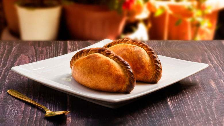 two salteñas on a white plate