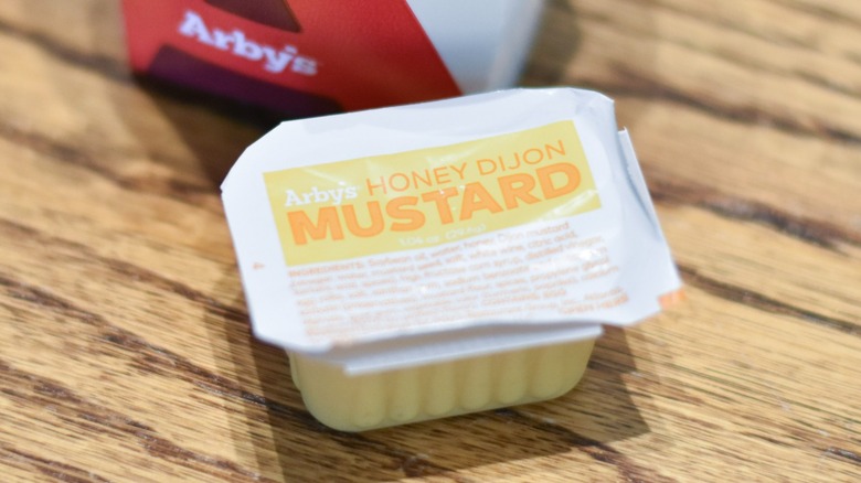 A carton of honey mustard on a wooden table