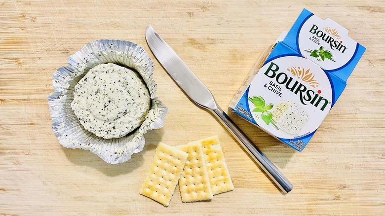 Open package of Boursin Basil & Chive with knife and crackers